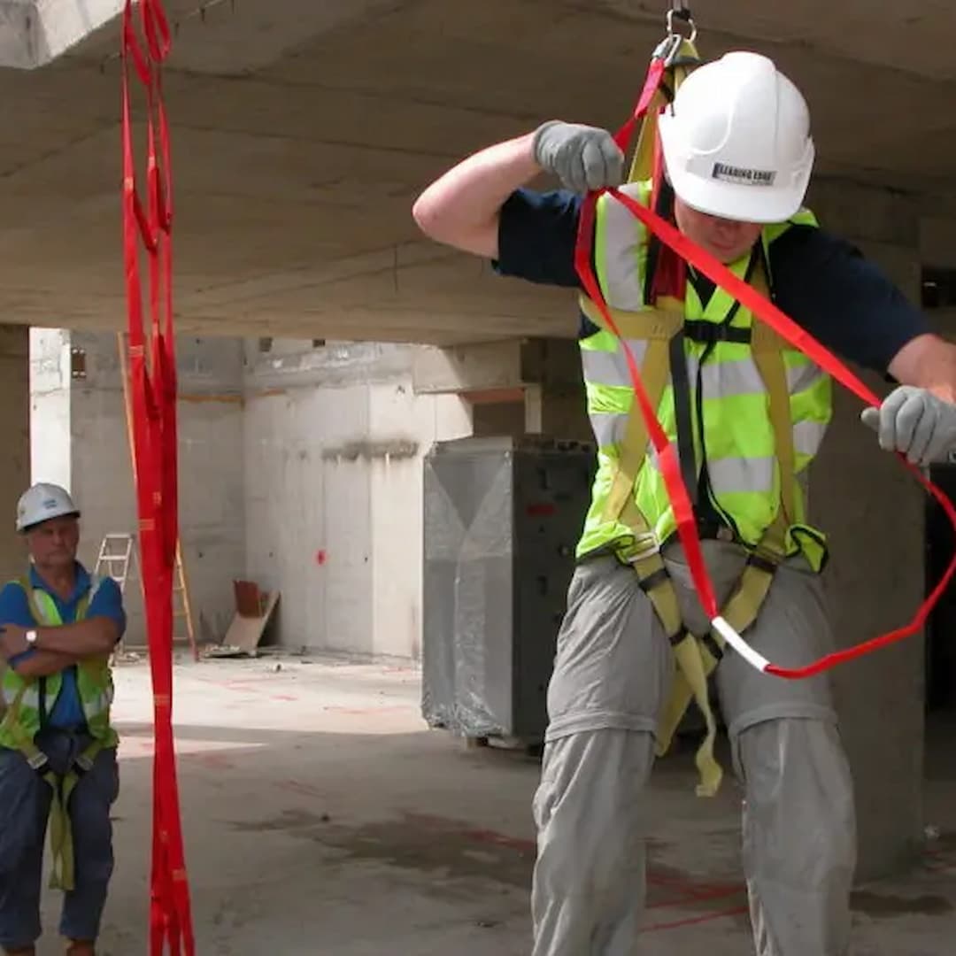 Worker in fall arrest position wearing height safety PPE and displaying connector